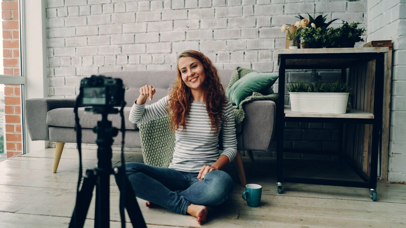 A creator waving at her camera from her living room