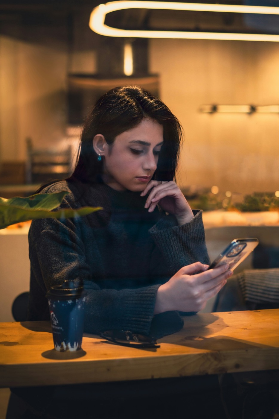 A woman at a café table, reading something on her phone